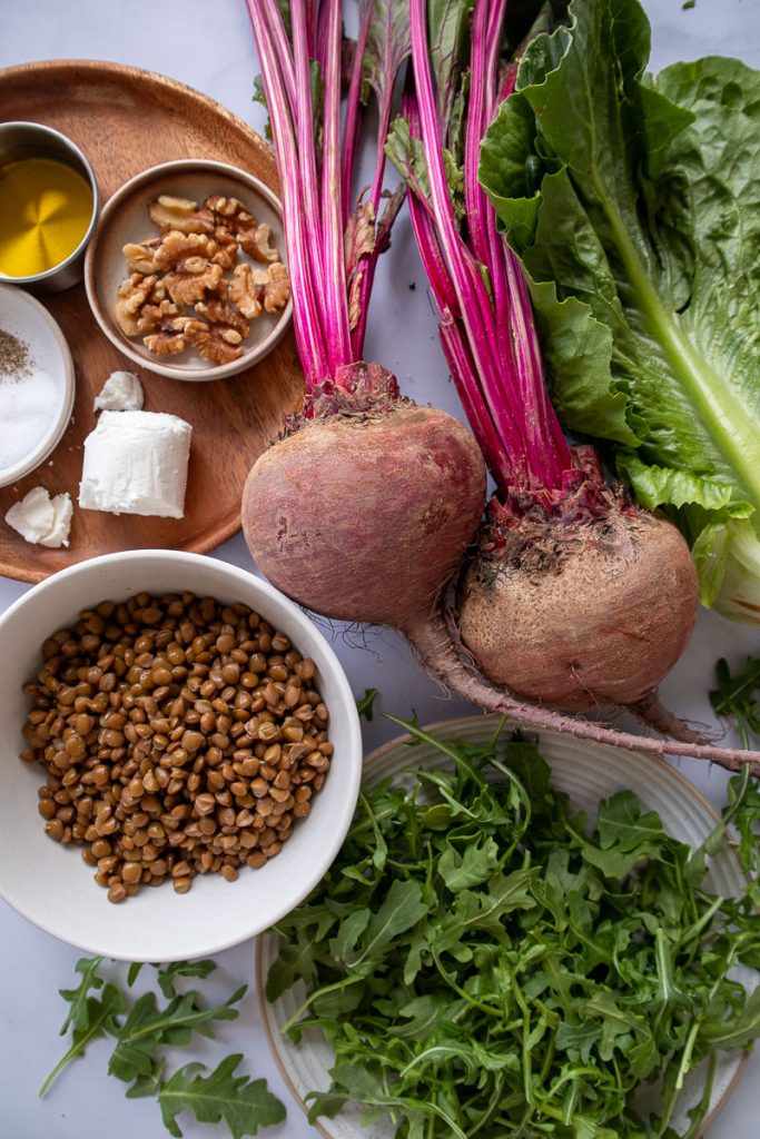 The ingredients for beetroot lentil salad including beets, lentils, arugula, romaine lettuce, walnuts, and goat cheese.