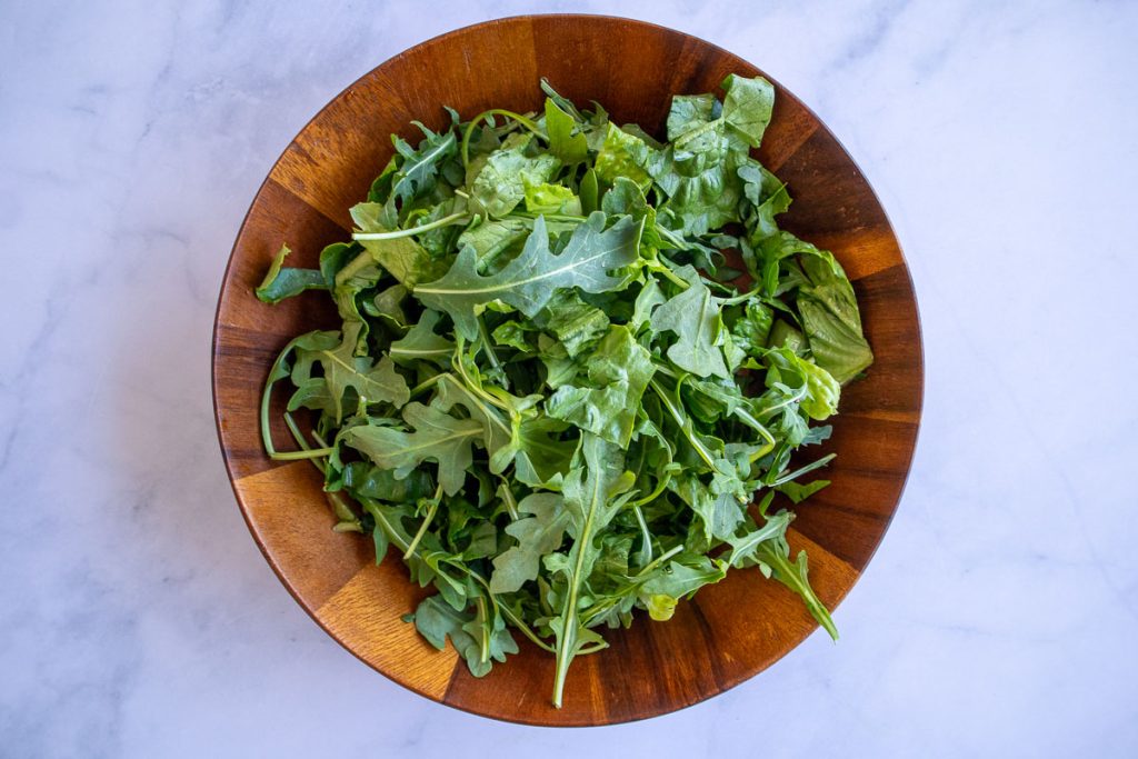 A wooden bowl with romaine and arugula.