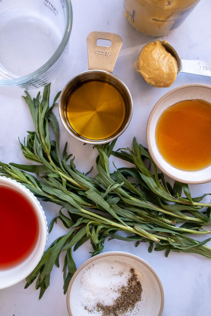 Ingredients for Tarragon Vinaigrette including fresh tarragon, dijon mustard, olive oil, red wine vinegar, maple syrup, salt and pepper.