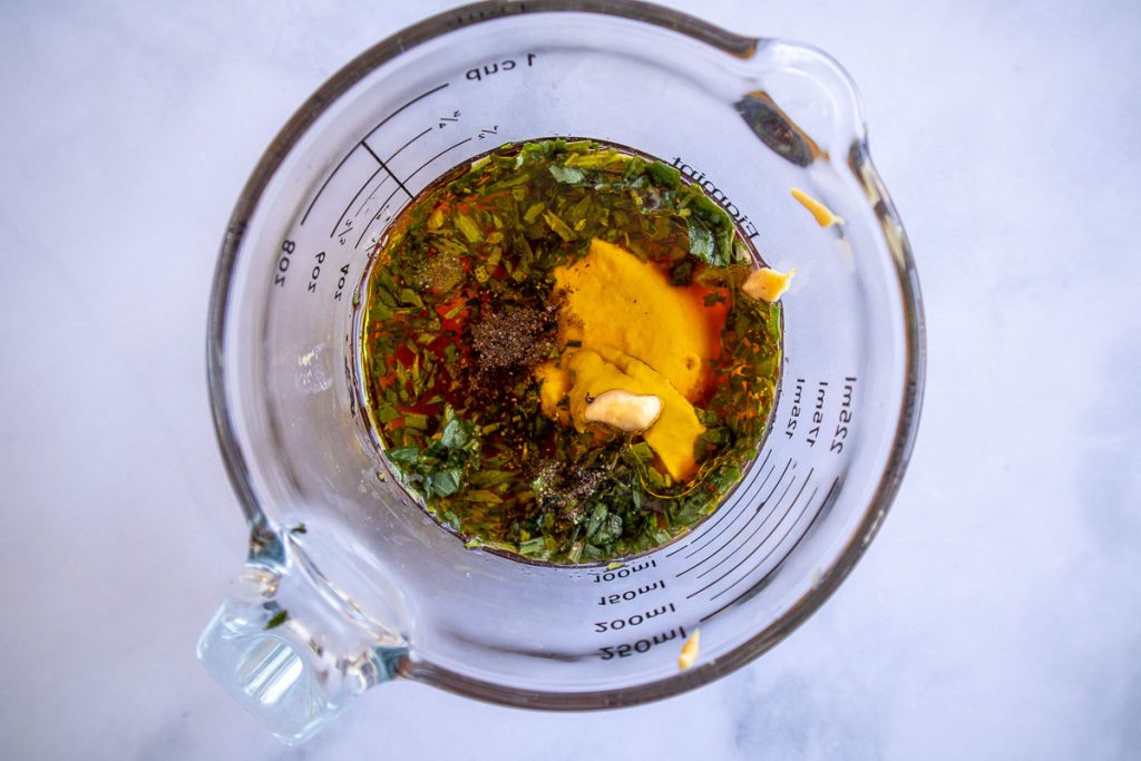 A measuring cup with the ingredients for tarragon vinaigrette before mixing.