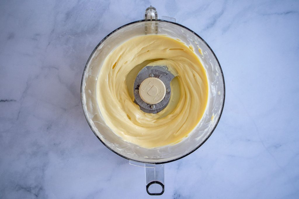 An overhead shot of a food processor bowl with freshly made mayo.